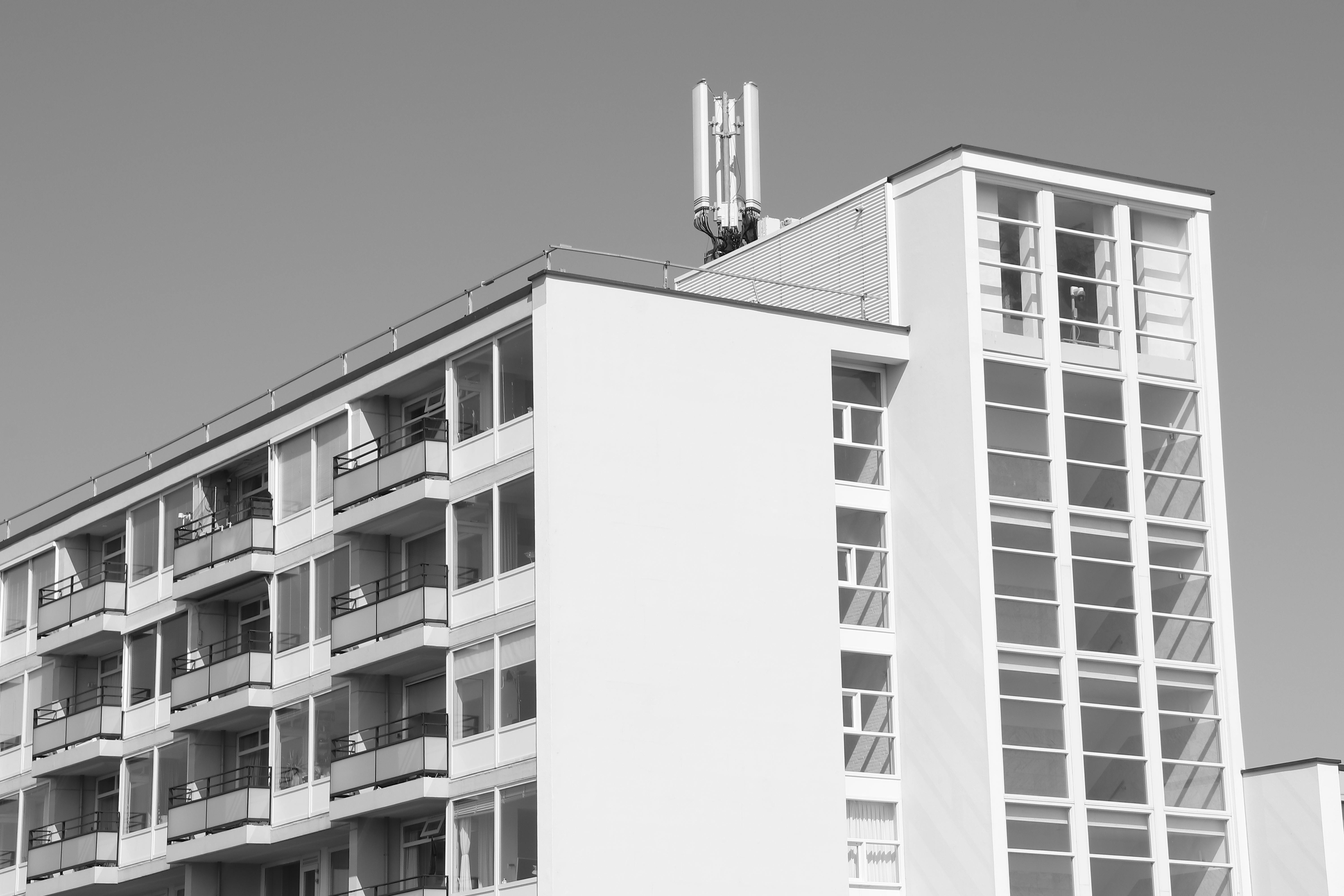 Minimalist black and white photo of modern apartment building with cellular tower.